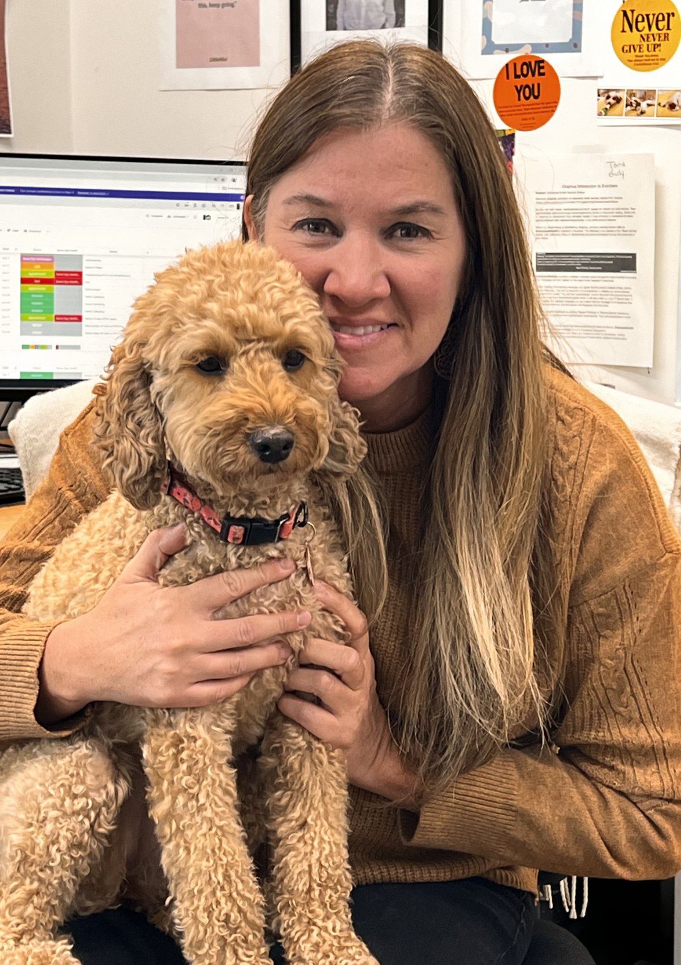 Beth smiling with her dog at her desk