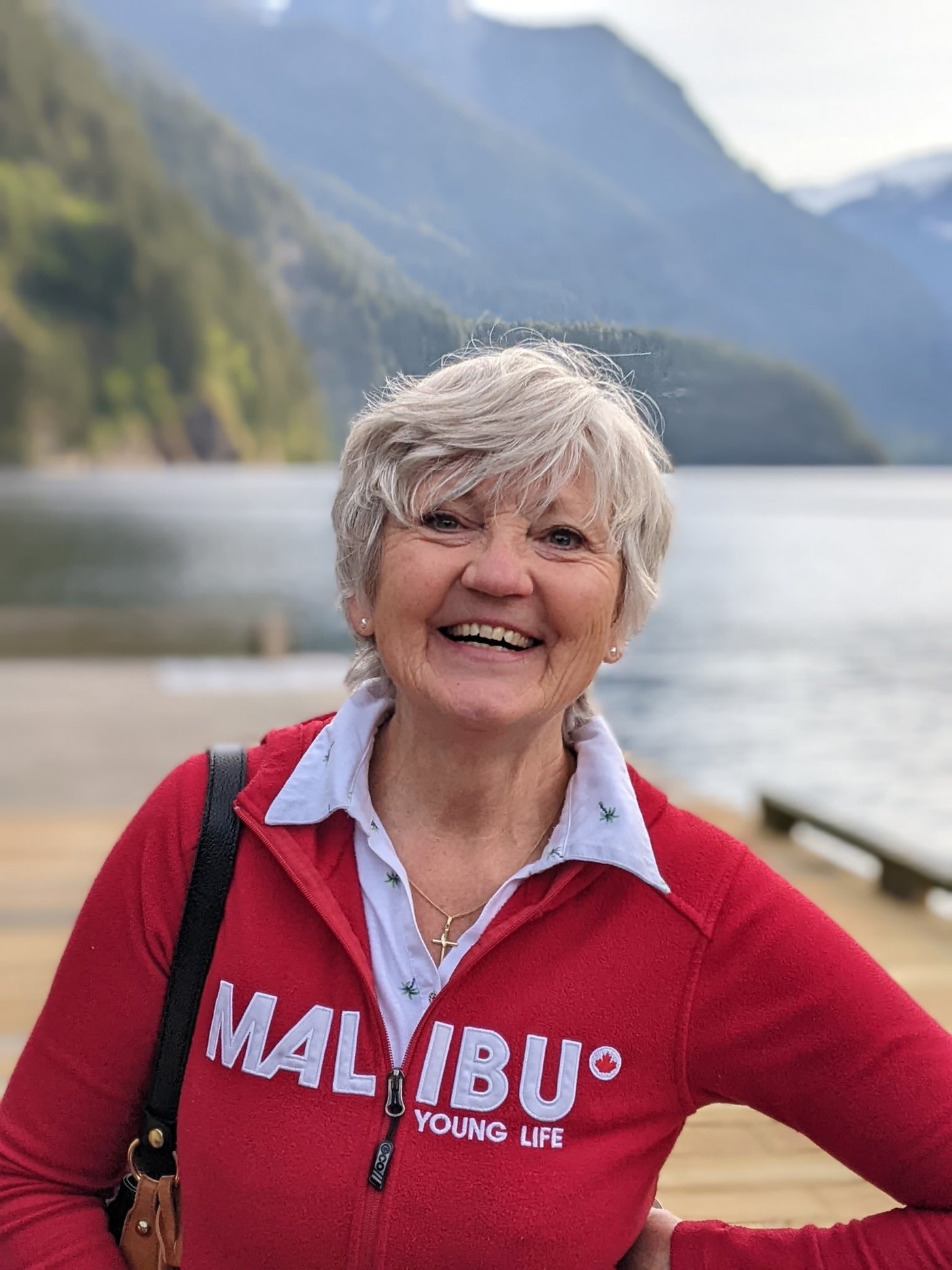 Ewa smiling outdoors by a mountain lake