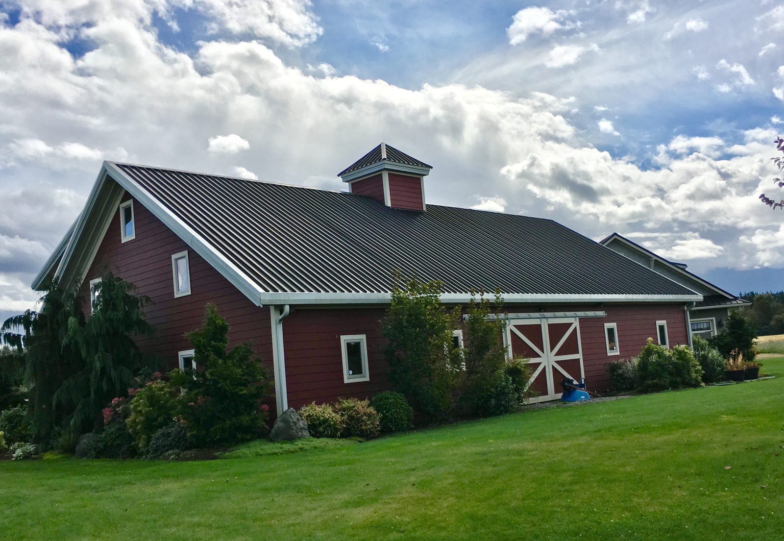 Red steel barn-style building with a cupola and covered entry