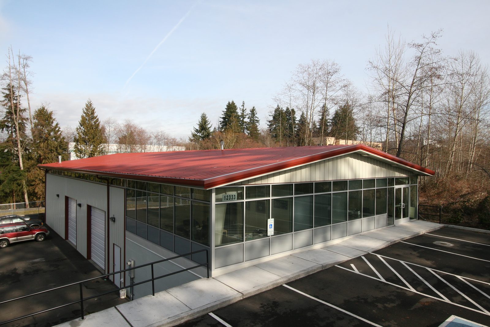 Steel building with a red roof and large storefront glass windows