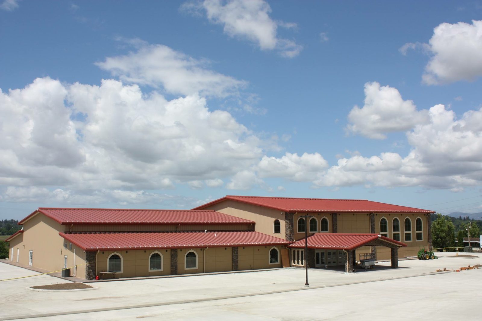 Large steel building with a red roof and arched windows used as an assembly hall
