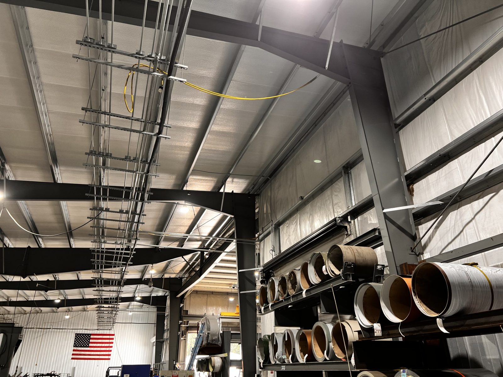 Interior of a steel warehouse with exposed framing and stored material reels